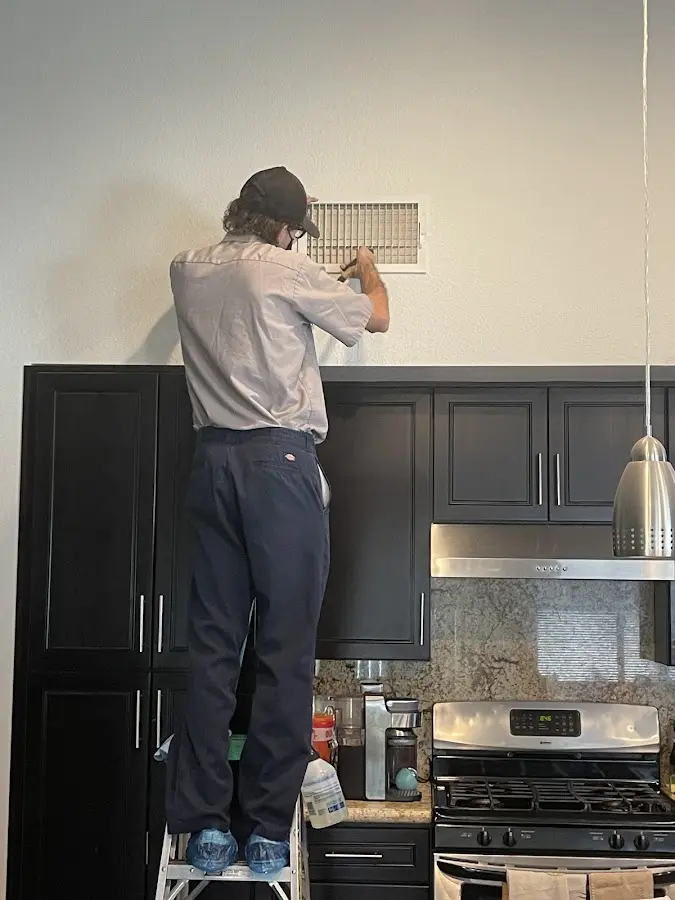 Technician inspecting an air vent during HVAC service in North Whitehall